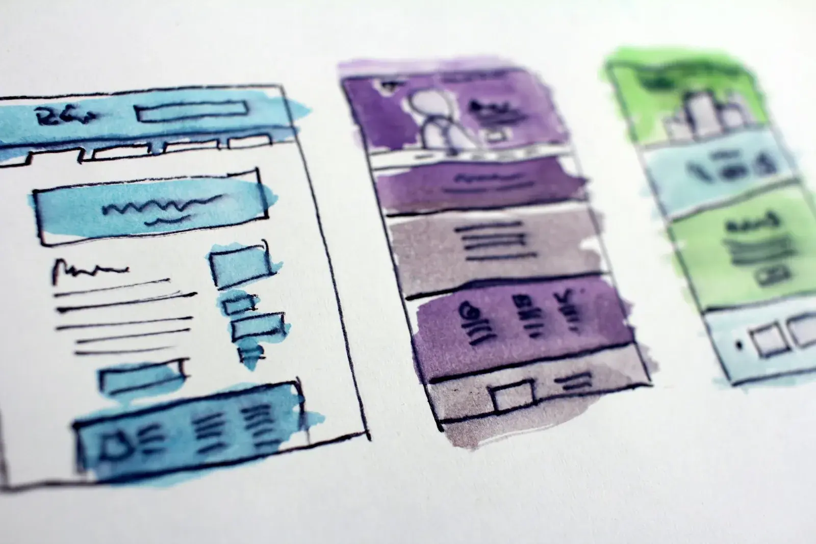 Watercolor wireframe sketches showing the layout of three different website pages.