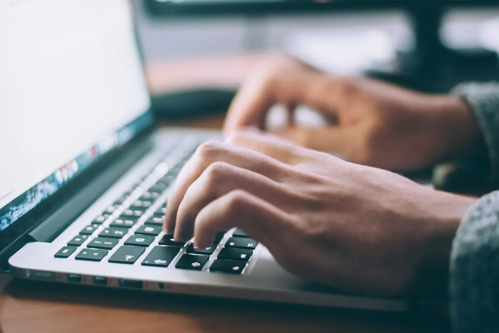 Someone typing on a laptop keyboard, a document open on the screen.