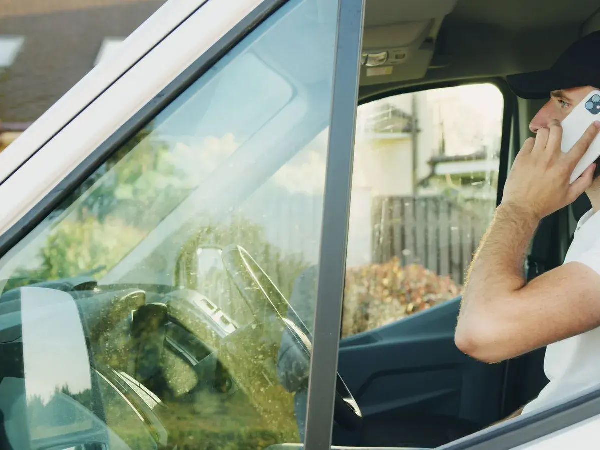 A tradesperson taking a call from the cab of his van.