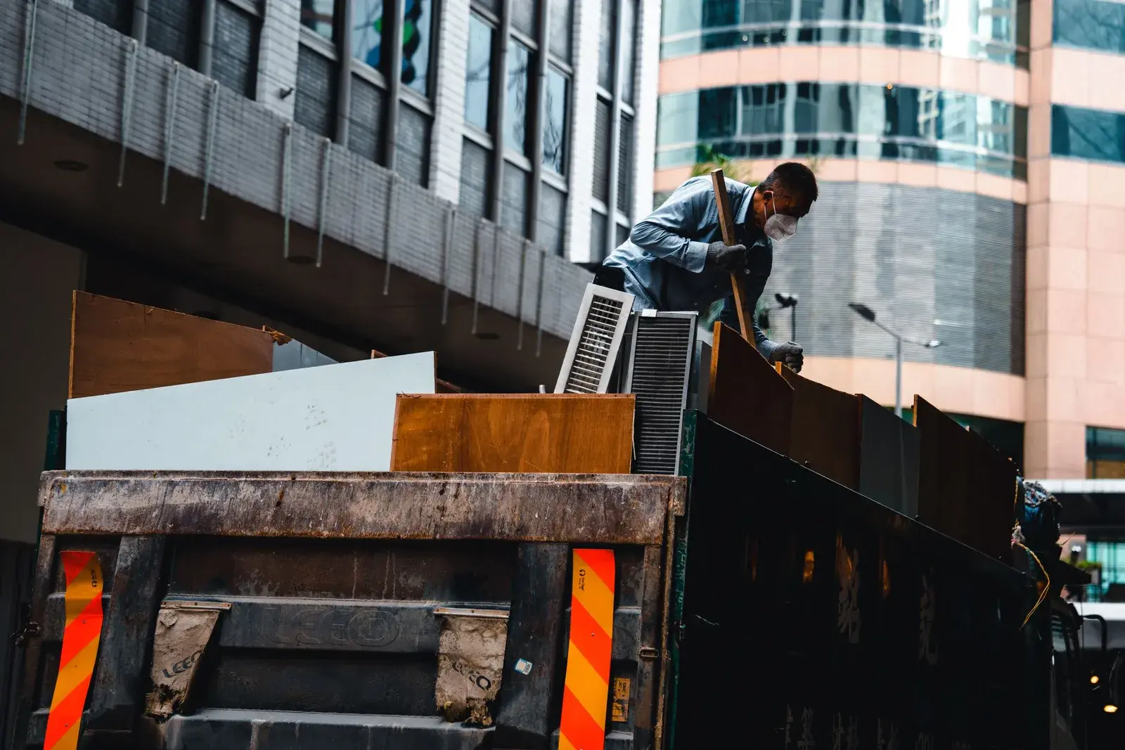 A worker loading construction debris onto the bed of a truck during a clearance.