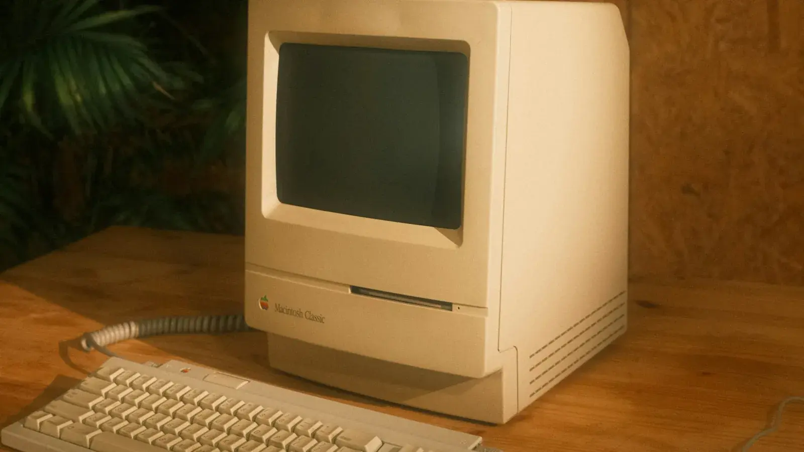 An old Macintosh Classic computer sitting on a wooden desk.